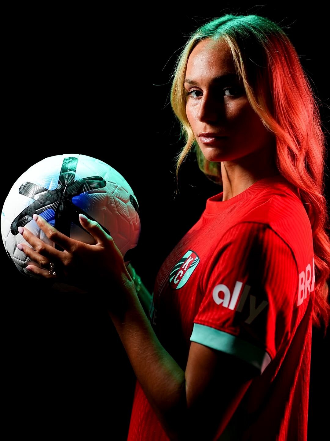 Ellie Bravo-Young in the red Kansas City Current kit, holding a match ball